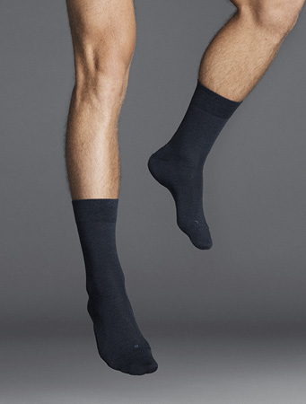 Mann trägt schwarze Socken der Marke FALKE und man sieht nur ein Close Up seiner Füße