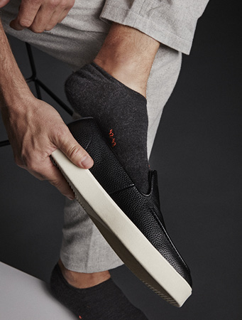 Mann trägt schwarze Sneakersocken der Serie Keep Warm von FALKE und zieht sich einen Schuh an
